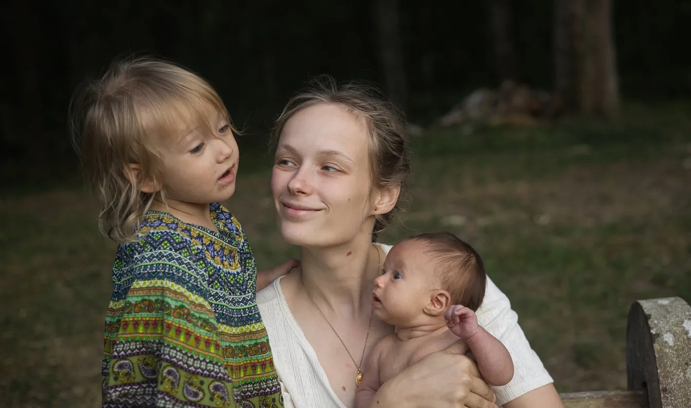 Calypso Bonnefoy en forĂȘt, sa fille aĂźnĂ©e blottie contre elle et son nouveau-nĂ© dans les bras